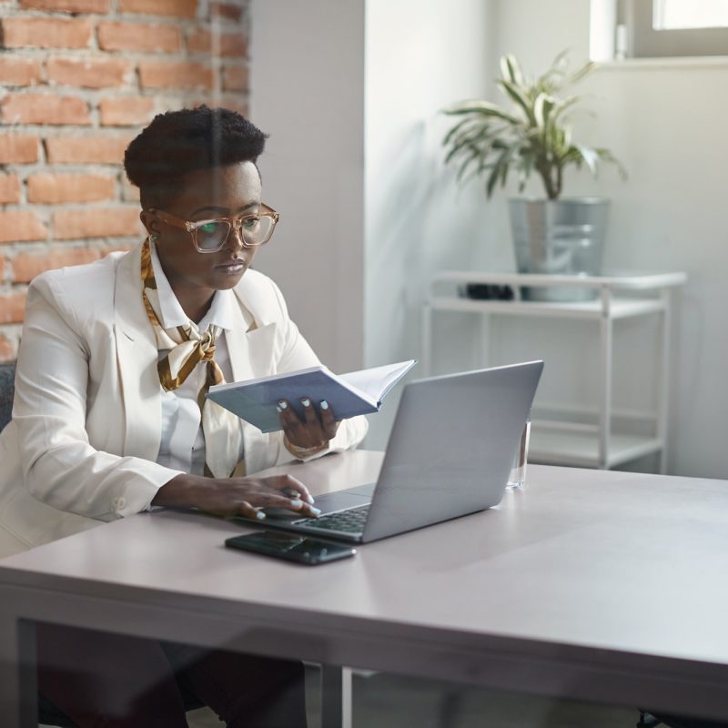 Black businesswoman working on laptop at corporate office.